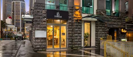 A hotel with a stone facade, a sign reading 'ZODIAK,' and a visible entrance.