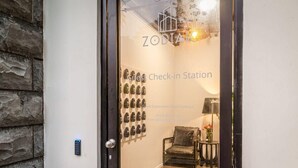A guest check-in station with a stone wall and a wall-mounted display of items. - Superking Bed in Stylish Apartment I Zodiak Stays (Auckland)