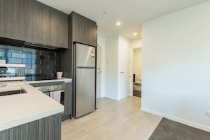A modern kitchen with a built-in microwave, a stainless steel refrigerator, and a wooden backsplash. - Park Views in CBD Next to Myers Park by Zodiak (Auckland)