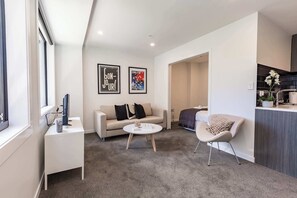 A modern living room with a sofa, a coffee table, and a chair. There are two framed pictures on the wall.