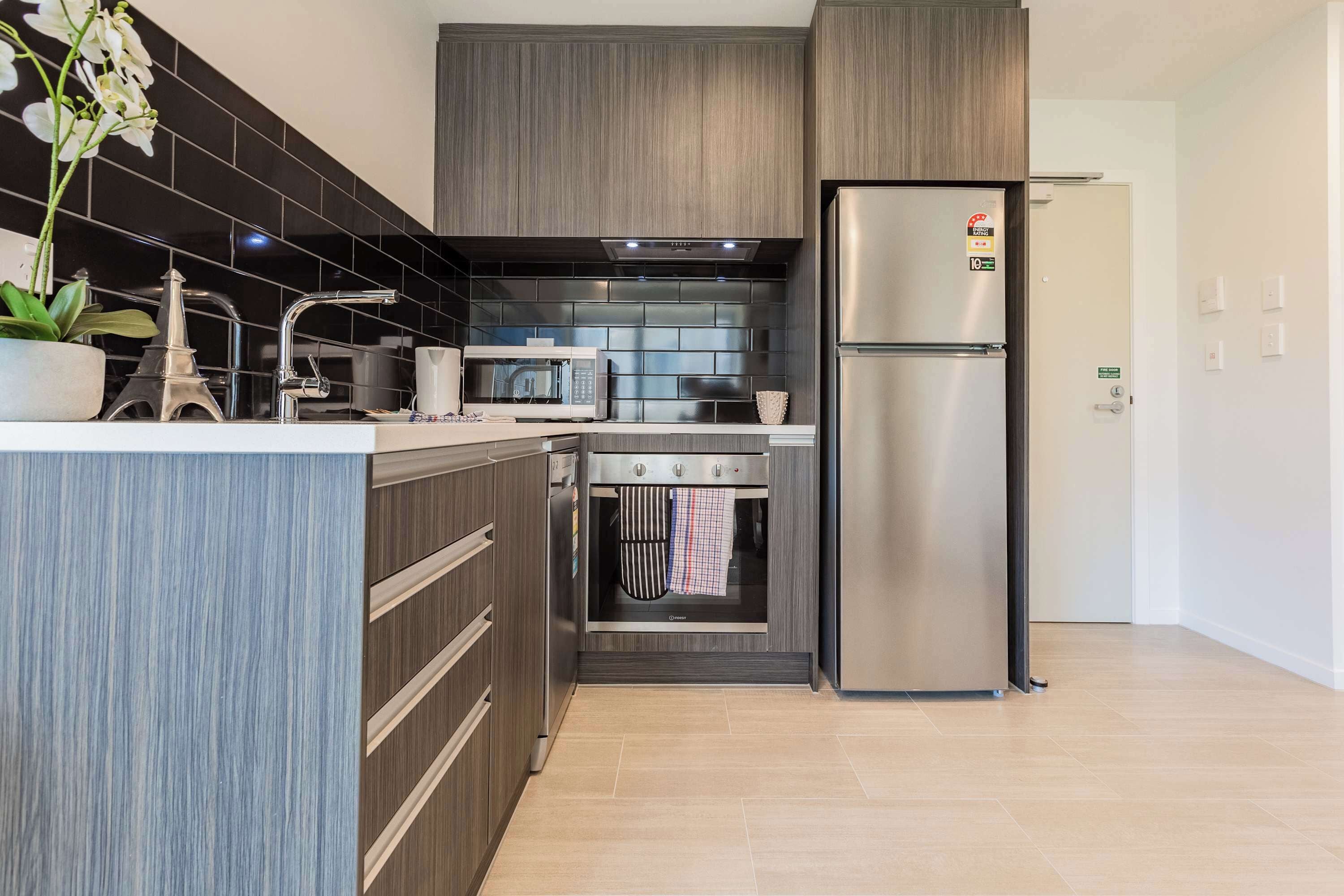 Een moderne keuken met een inbouwoven, magnetron en een koelkast van roestvrij staal.
