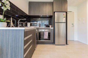 A modern kitchen with a built-in oven, microwave, and stainless steel refrigerator.