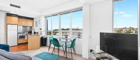 A modern apartment with a kitchen, dining area, living room, and large windows offering a city view.