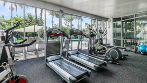 Une salle de sport équipée de tapis de course, de vélos d’appartement et de ballons d’exercice.