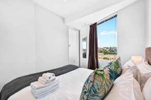 Ein Hotelzimmer mit Bett, Fenster mit Blick, Tür und Nachttisch.