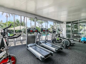Une salle de sport équipée de tapis de course, de vélos d’appartement et d’autres appareils d’exercice.