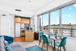 A modern apartment with a kitchen, dining area, and a large window offering a city view.