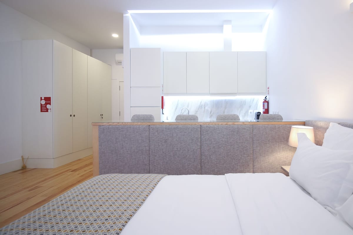 Una habitación de hotel moderna con una cama grande, una kitchenette pequeña y un baño.