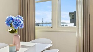 Ett hotellrum med ett stort fönster, en vas med blommor, ett bord och stolar.