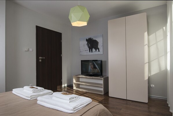 Un dormitorio moderno con cama, televisor, armario y un cuadro de un caballo.