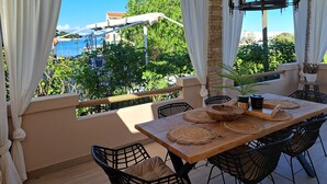 Un balcon avec une table en bois, des chaises et un luminaire suspendu.