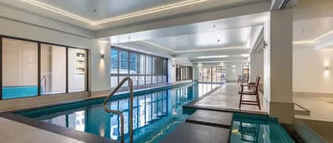 An indoor swimming pool with clear water, tiled walls, and a long poolside area.