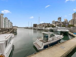 A marina with several boats docked, a clear sky, and buildings in the background. - Beautiful 2BR - Pool, Gym & Parking Zodiak Stays (Auckland)