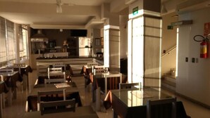 Un vestíbulo moderno de hotel con un área de estar central, una escalera y una cocina visible al fondo.