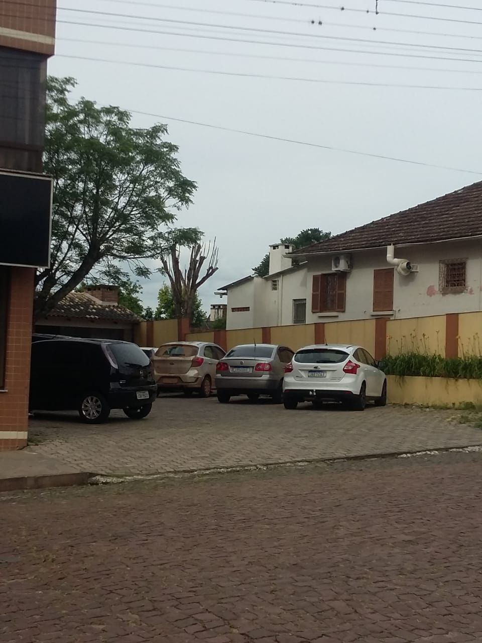 Una zona residencial con un camino pavimentado, autos estacionados y un edificio con techo de tejas.