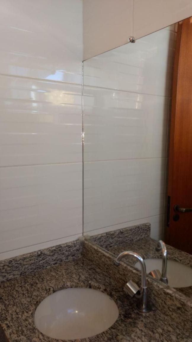 Un baño con paredes de azulejos blancos, encimera de granito y lavamanos con grifo.
