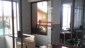Una sala de estar moderna con un separador de vidrio, un sofá, una mesa de centro y un comedor a la vista a través del vidrio.