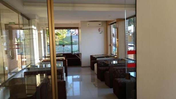 Un vestíbulo de hotel moderno con divisiones de vidrio, asientos cómodos y grandes ventanales que ofrecen vistas al exterior.