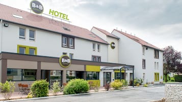 Un hotel B&B con diseño moderno, que presenta un techo plano, ventanas amplias y un jardín bien cuidado.