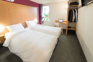A hotel room with two beds, a desk, a chair, a wardrobe, and a window.