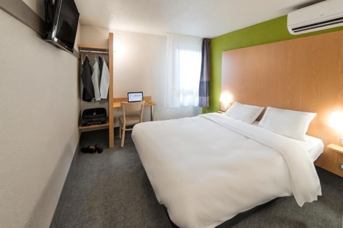 Une chambre d’hôtel équipée d’un lit, d’un bureau, d’une chaise, d’un téléviseur et d’un appareil de climatisation.