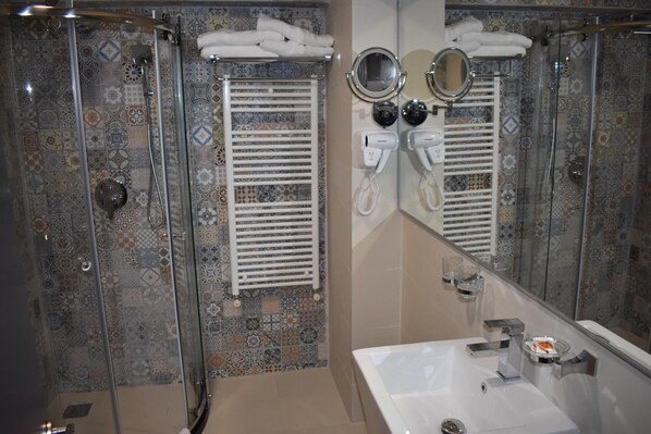 Baño con ducha, dos secadores de pelo y un lavabo.