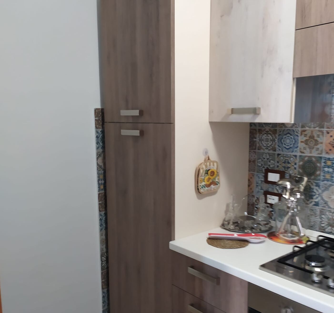 Eine Küche mit Holzausbau, einer weißen Arbeitsplatte und einer gefliesten Spritzschutzwand.