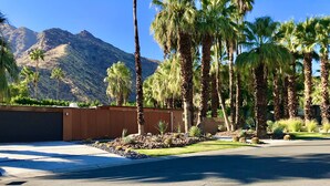 A residential area with a driveway, palm trees, and a mountain in the background. - Rose Vista Las Palmas Special Summer Rates Now In Effect (Palm Springs)
