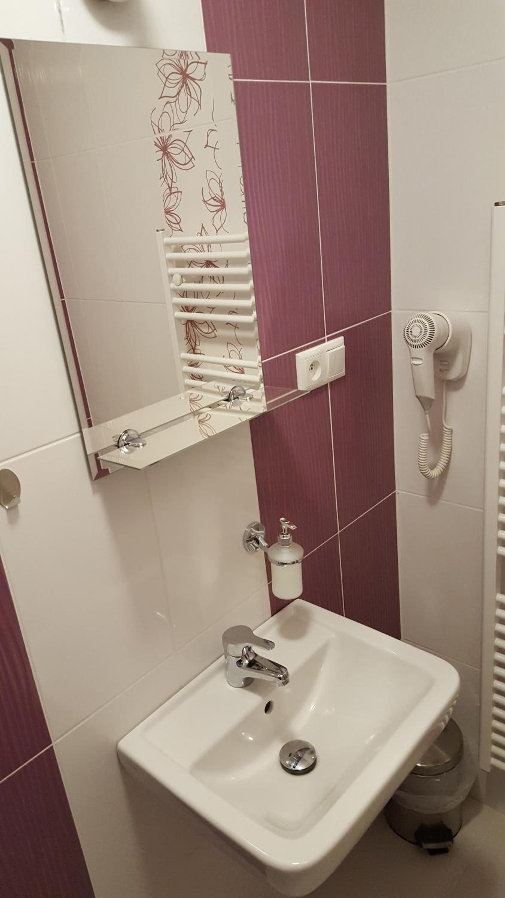 Un baño con un lavabo blanco, un espejo, toallero, inodoro y secador de pelo.