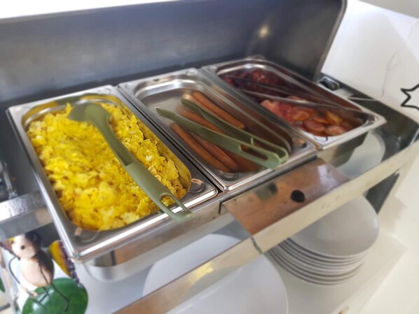 A buffet with scrambled eggs, sausages, and bacon. - Penzión Galéria (Bojnice)