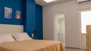 Un dormitorio con una cama, una mesita de noche, una lámpara y dos cuadros en la pared.