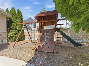 A wooden playground with a slide and climbing wall.