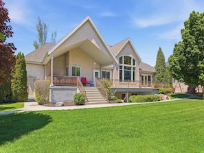 A two-story house with a covered porch, a front staircase, and a well-maintained lawn.