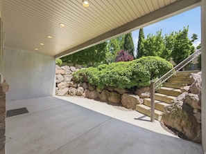 A covered outdoor area with a stone wall, greenery, and a staircase.