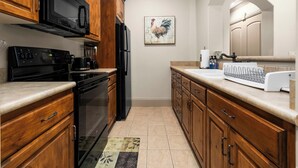 A kitchen with wooden cabinets, a black microwave, a stove, and a refrigerator. - Luxury Basement Full Apartment with Private Entrance (Provo)