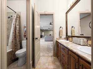 A bathroom with a toilet, shower, vanity with a sink, and a large mirror.
