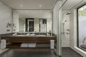 A modern bathroom with a double sink vanity, a large mirror, a walk-in shower, and a potted plant. - Dusit Thani Lubi Plantation Resort (Mabini)