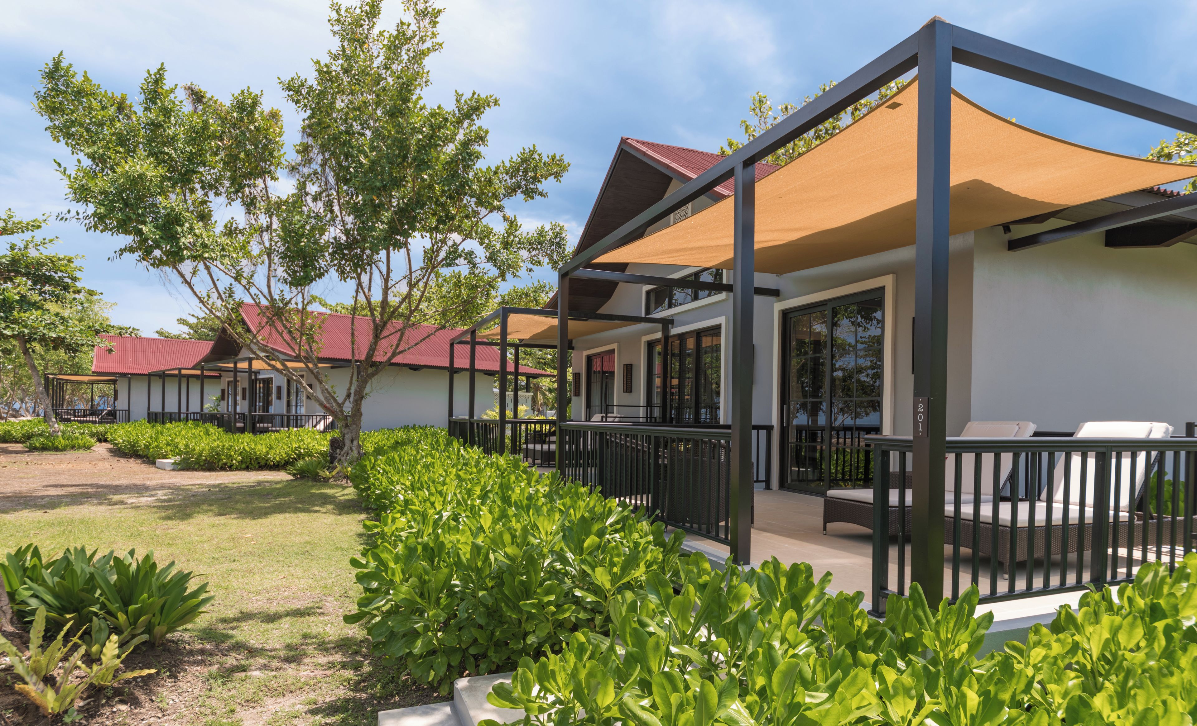 A modern building with a covered outdoor seating area, surrounded by well-maintained greenery.
