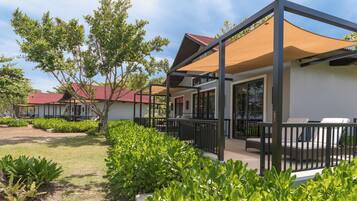A modern building with a covered outdoor seating area, surrounded by well-maintained greenery.