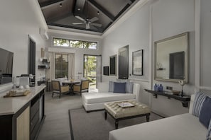 A modern hotel room with a dining area, a large mirror, and a view of the outdoors.