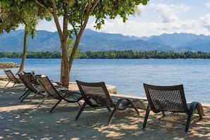 A beach with lounge chairs and a view of mountains.
