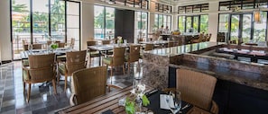 A spacious restaurant with high ceilings, large windows, and a central island.