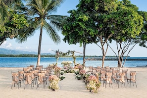 A beach wedding setup with chairs and floral decorations.