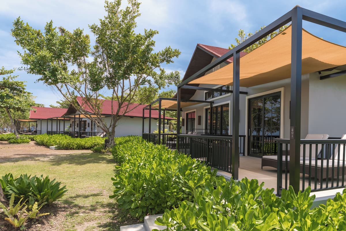 A modern building with a covered outdoor seating area, surrounded by well-maintained greenery.