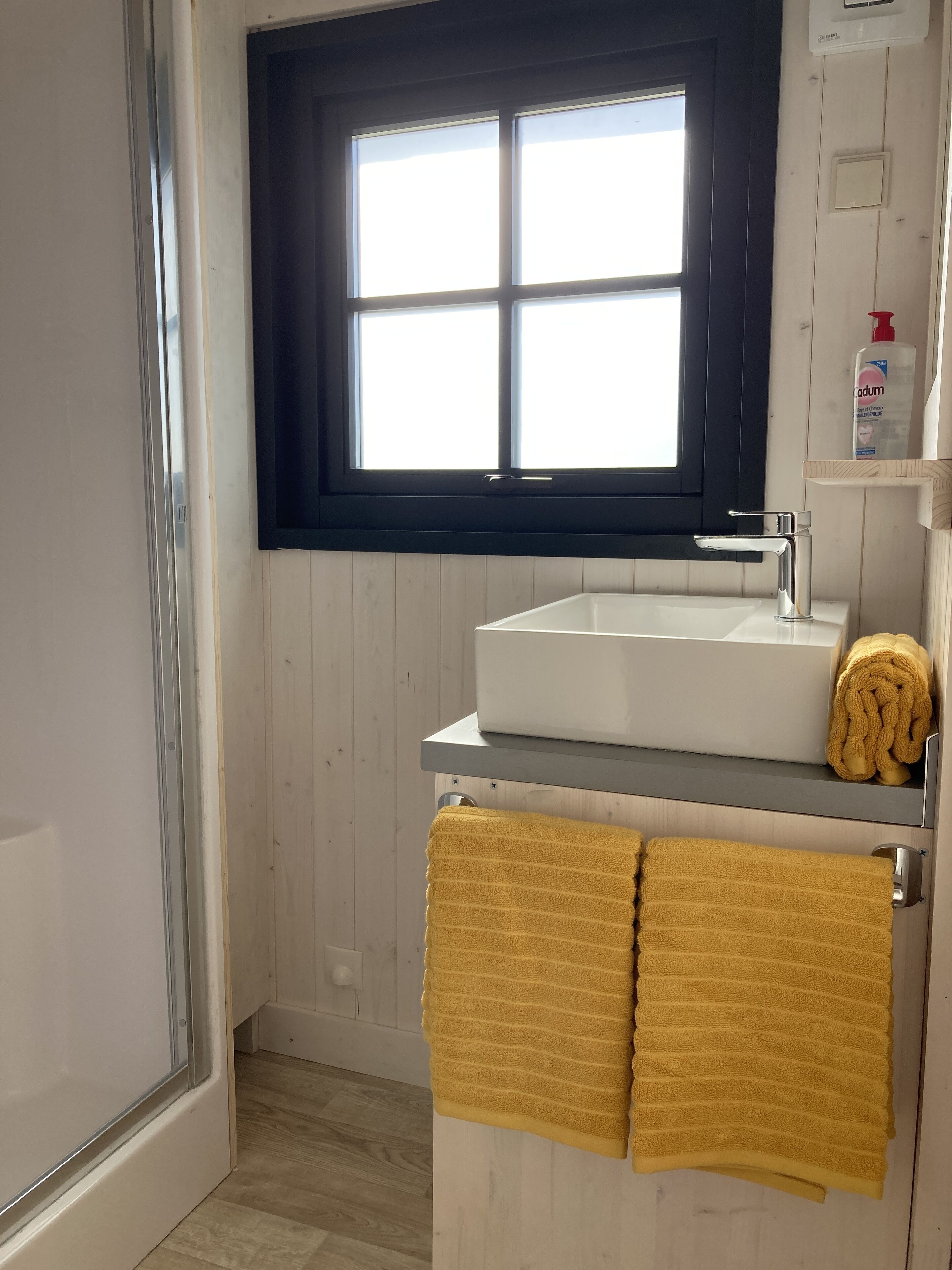 Ein Badezimmer mit Fenster, Waschbecken und Handtuchhalter.