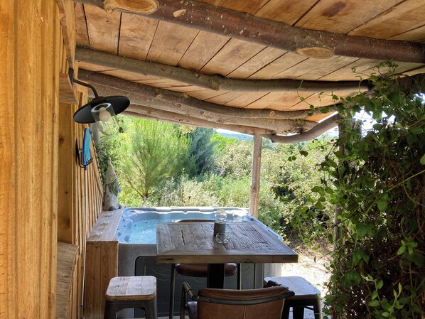 A wooden outdoor seating area with a hot tub, wooden tables, and chairs. - Cabanes Trésors de Campagne (Villarzel-du-Razes)