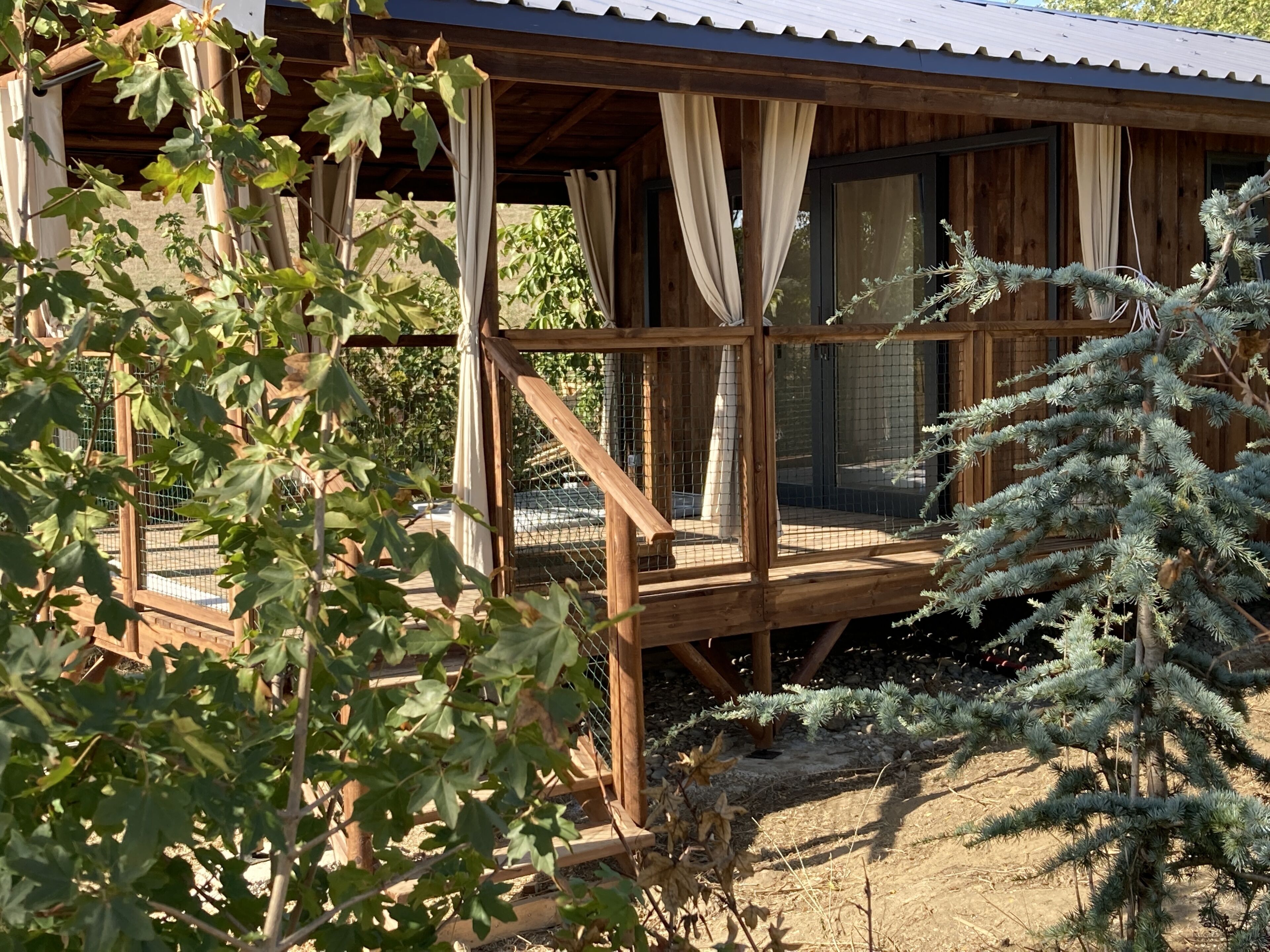Una cabaña de madera con balcón, ventanas amplias y un porche cubierto.