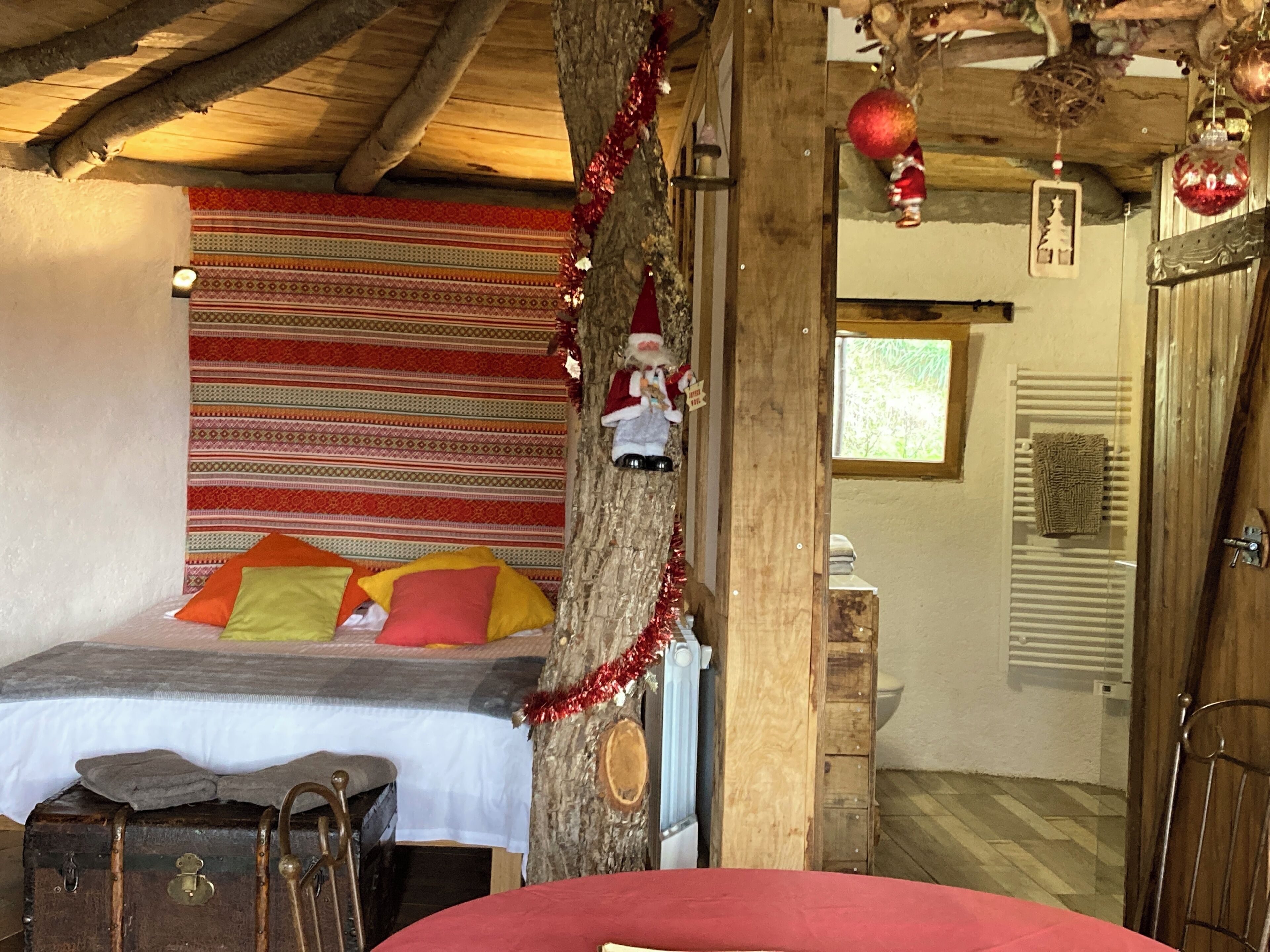 Ein gemütliches Zimmer mit einem Bett, einem Holzkoffer und einem Weihnachtsbaum.