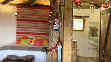 Ein gemütliches Zimmer mit einem Bett, einem Holzkoffer und einem Weihnachtsbaum.