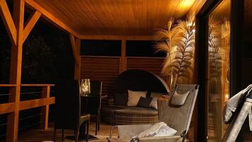A cozy outdoor seating area with wooden furniture, a cushioned bench, and a decorative vase.